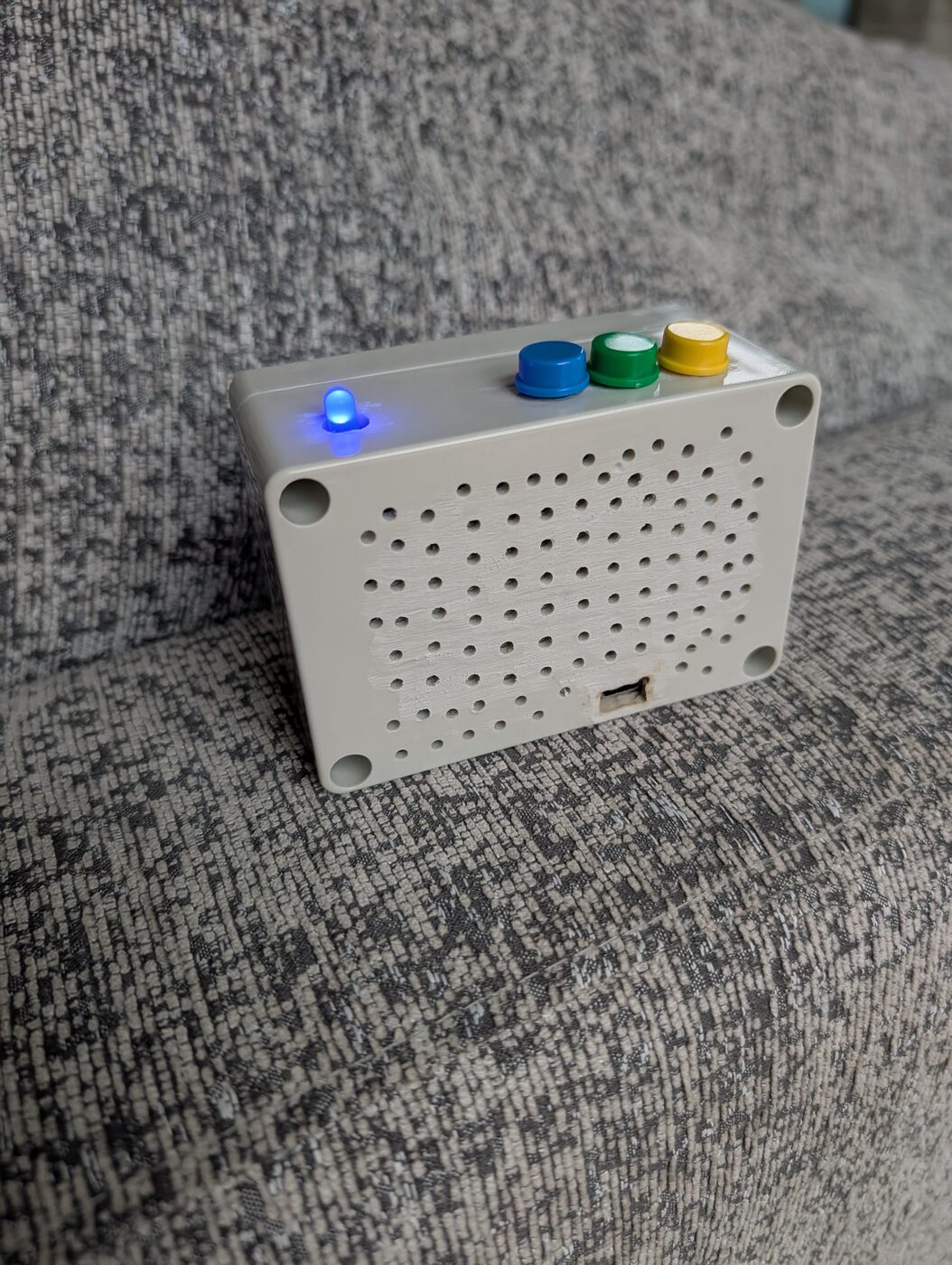 The back of the box showing a grid of hand-drilled speaker holes and a USB port.